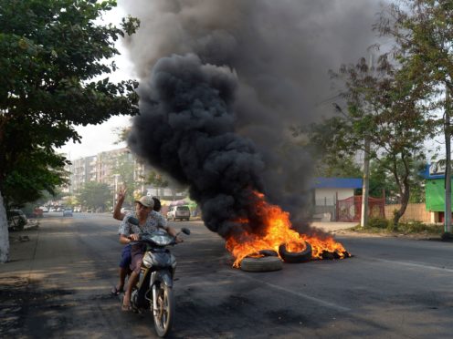 Anti-coup protesters pass burning tires in Yangon (AP)
