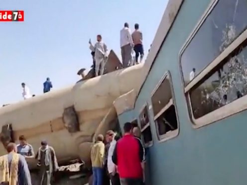This image provided by Youm7 shows crowds of people gathered around mangled train carriages at the scene of a train accident in southern Egypt, Friday, March 26, 2021. Two trains collided apparently after someone activated the emergency brakes, killing several people and leaving others injured, Egyptian authorities said. (Youm7 via AP)