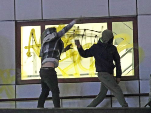 Protesters on a roof throw objects down at police outside Bridewell Police Station (Andrew Matthews/PA)