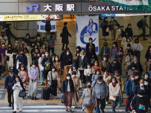 People wear face masks as they make their way in Osaka, western Japan (Kyodo News via AP)