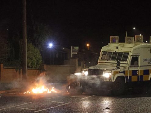 The PSNI moving a bin which was set alight on North Road in Carrickfergus near Belfast following sporadic outbursts of disorder. Picture date: Sunday April 4, 2021.