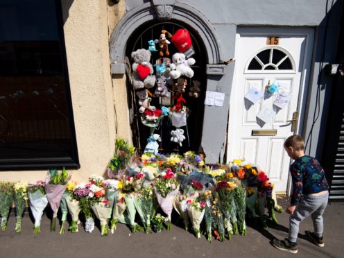 A boy lays flowers at the scene on High Street, Brownhills, near Walsall in the West Midlands (Jacob King/PA)
