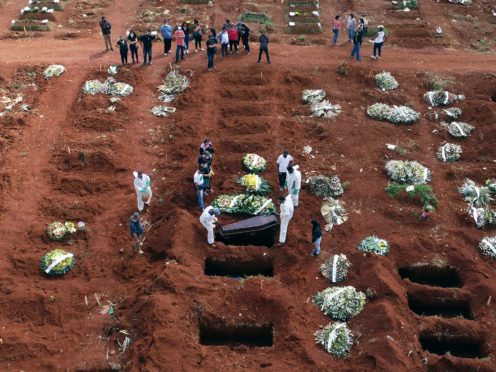 Cemetery workers wearing protective gear lower the coffin of a person who died from complications related to Covid-19 into a gravesite in Brazil (AP/Andre Penner)