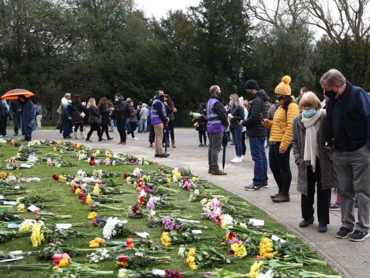 People stop to look at flowers left outside Windsor Castle (Gareth Fuller/PA)