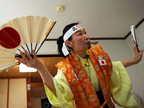 Olympic fan Kyoko Ishikawa shows her cheering at her home in Tokyo (Eugene Hoshiko/AP)