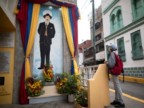 A woman prays close to a painting of Jose Gregorio Hernandez (Ariana Cubillos/AP)