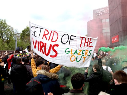 Fans hold up a banner as they protest against the Glazer family outside Old Trafford (Barrington Coombs/PA)