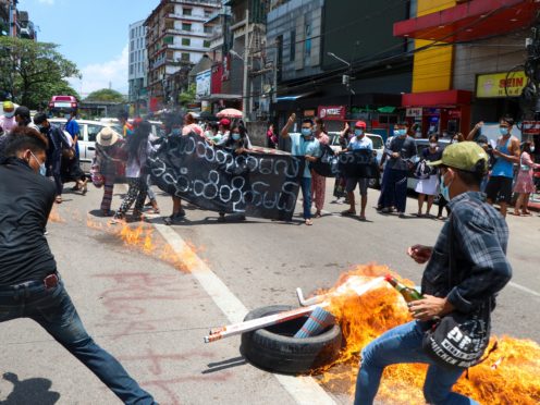Anti-coup protesters burn tires and chant slogans with banner read ”The Kamayut strike will be fight for to the end when we get victory” during the demonstration against the military coup in Kamayut township Yangon, Monday, May 3, 2021. (AP Photo)