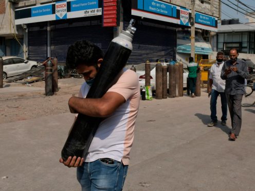 A man carries a refilled oxygen cylinder (Ishant Chauhan/AP)