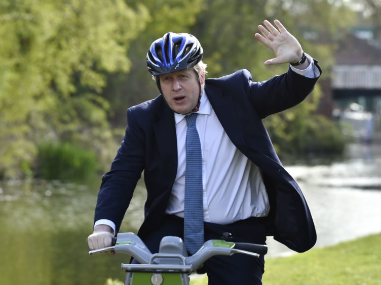 Prime Minister Boris Johnson waves as he rides a bike along the towpath of the Stourbridge canal in the West Midlands, whilst on the local election campaign trail (Rui Vieira/PA)