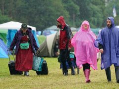 People cover up from the rain on the first day of Download Festival at Donington Park in Leicestershire (Joe Giddens/PA)