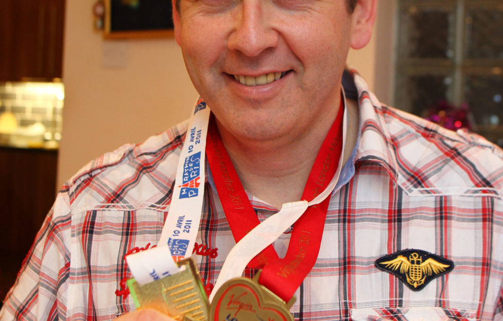 Bryn with his marathon medals - he says running helps the disease.