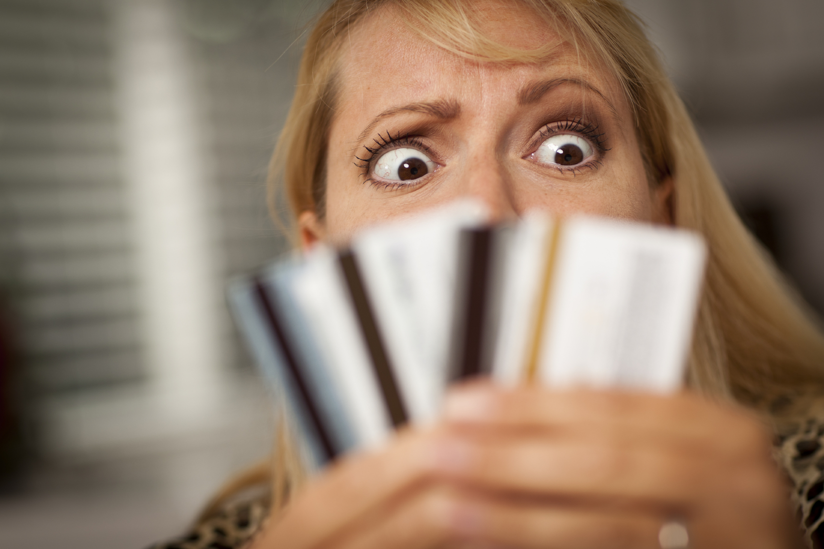 Upset Woman Glaring At Her Many Credit Cards.