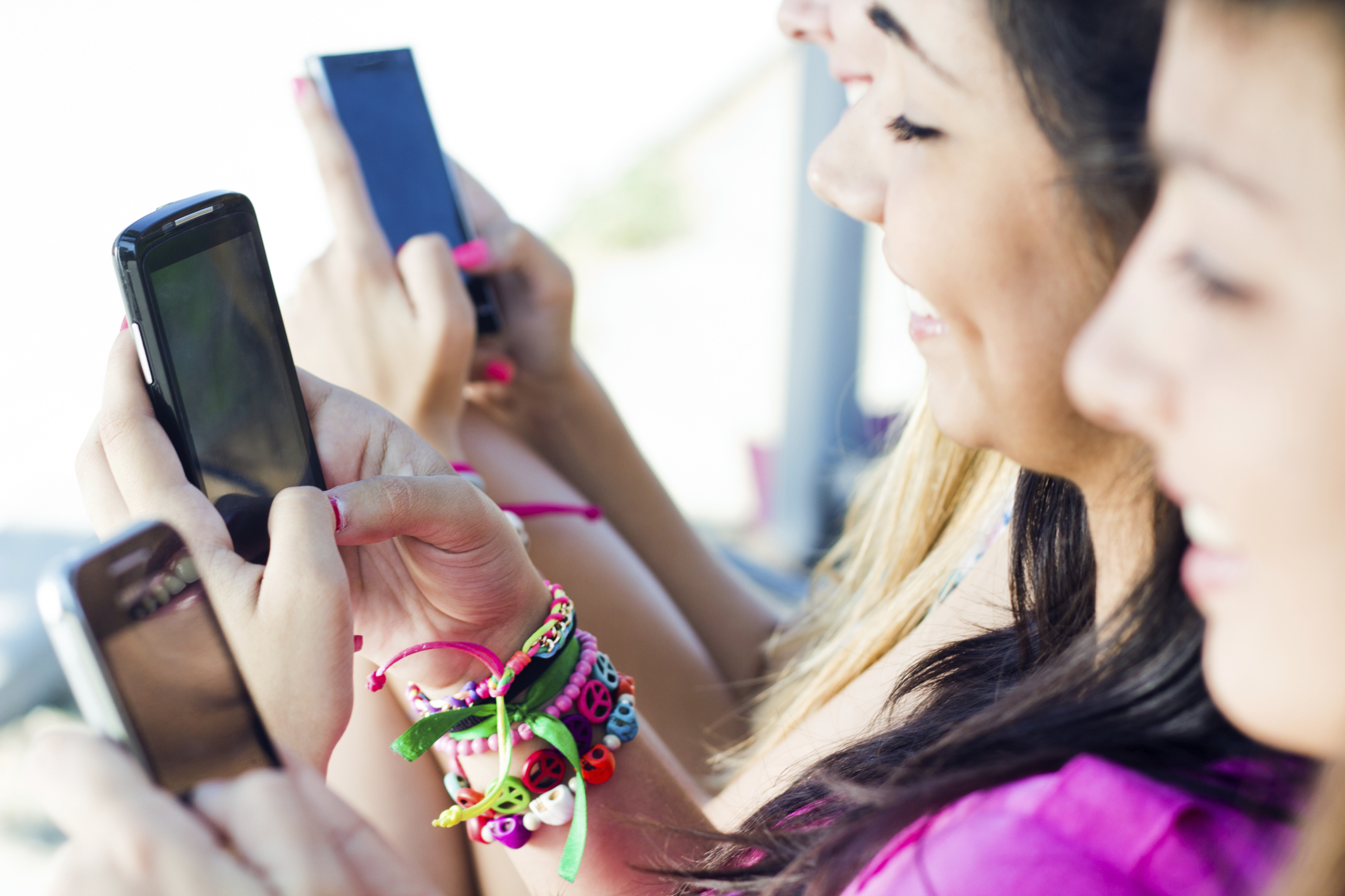 three girls chatting with their smartphones