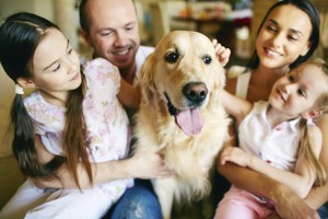 A young friendly family of four cuddling their pet