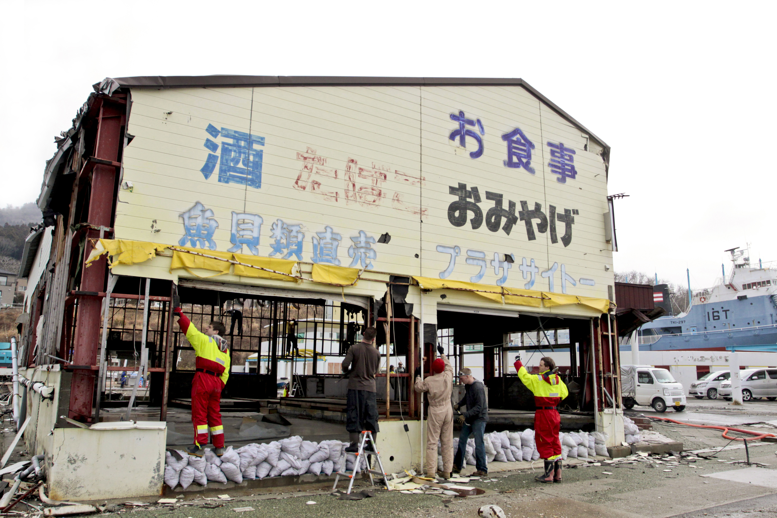 Volunteers remove old walls of what used to be a local souvenir shop and restaurant at a dock in Ishinomaki, Japan (U.S. Marine Corps photo by Lance Cpl. Benjamin Pryer)