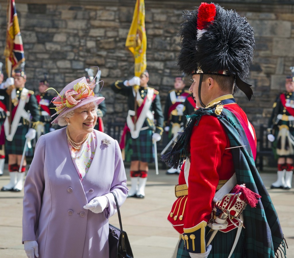 A smiling Queen Elizabeth is surrounded by soldiers in full Scottish dress at a commemorative service at the Scottish National War Memorial at Edinburgh Castle, 2014 (Chris Watt/Getty Images)