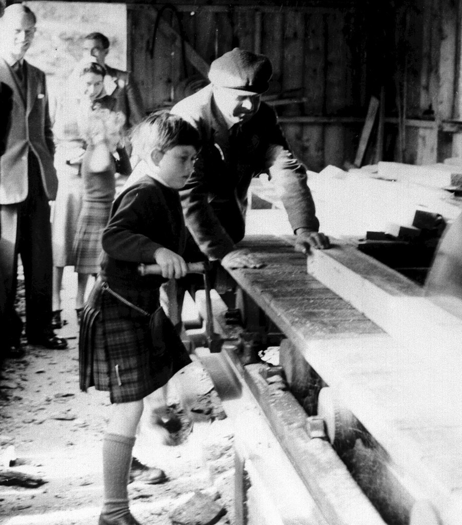 Eight-year-old Prince Charles tries his hand at the saw-mill on the Balmoral estate (PA Archive)