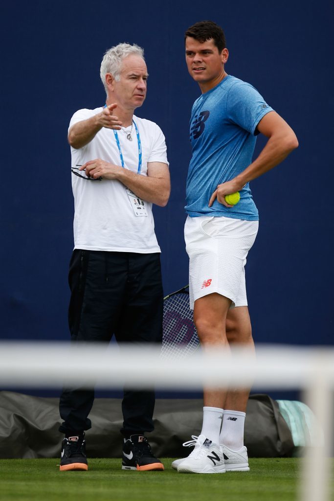 John McEnroe (L) speaks to Milos Raonic during a practice session (Joel Ford/Getty Images)