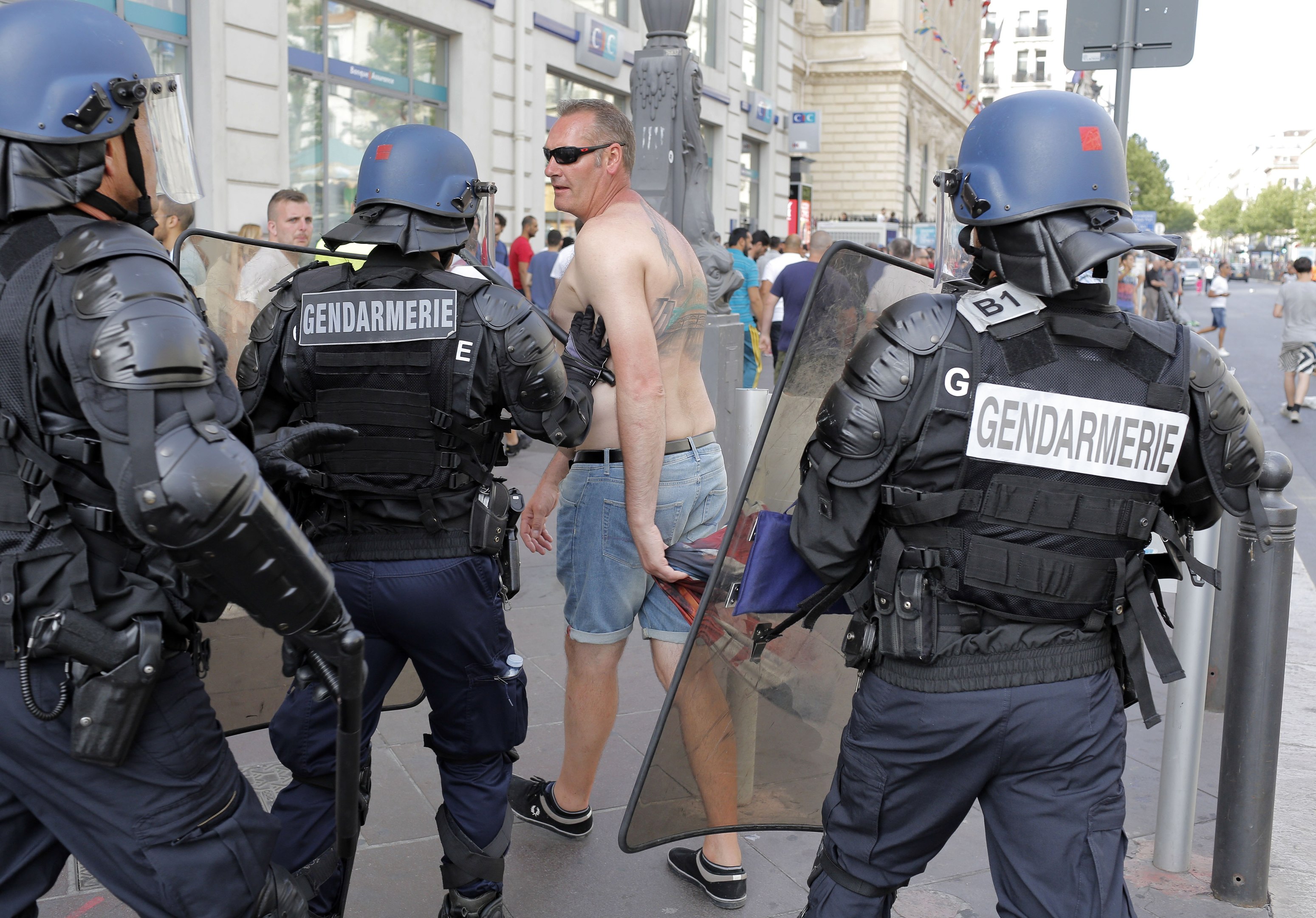 French riot police officers move along an England supporter in downtown Marseille, France, (AP Photo/Laurent Cipriani)
