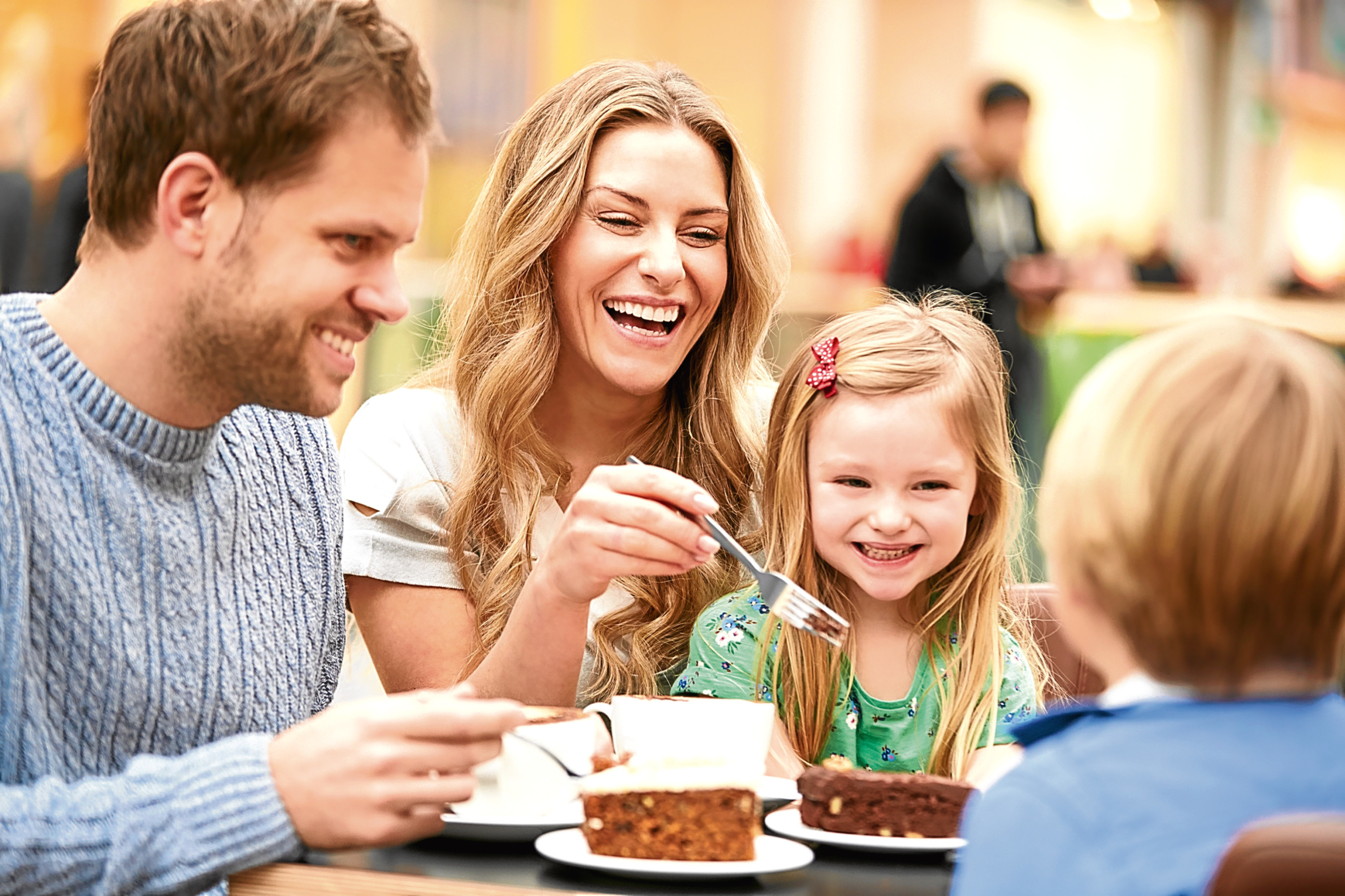 Family Enjoying Snack In Café Together Smiling