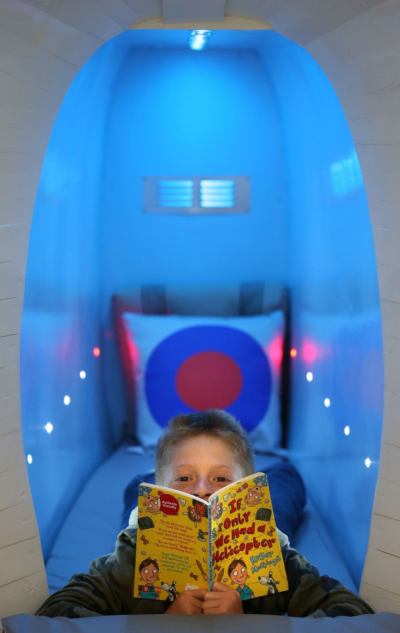 Nine year old Harry Steedman reads a book on the single bed in the tail section of the retired Sea King helicopter (Andrew Milligan/PA Wire)