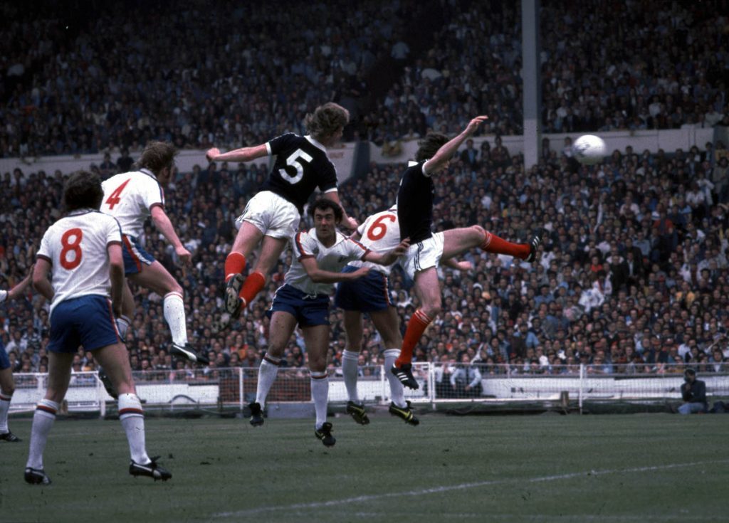 Gordon McQueen in action for Scotland, rises above Kennedy and Rioch (SNS Group)