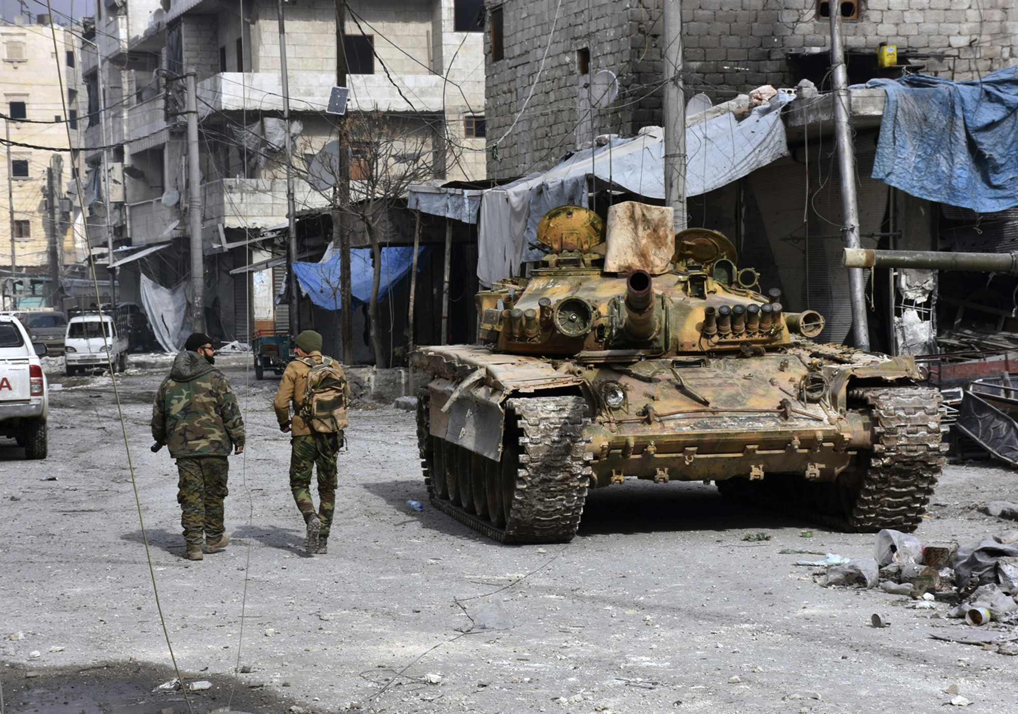 Syrian soldiers pass by a tank where government forces have captured wide areas in eastern Aleppo (SANA via AP)