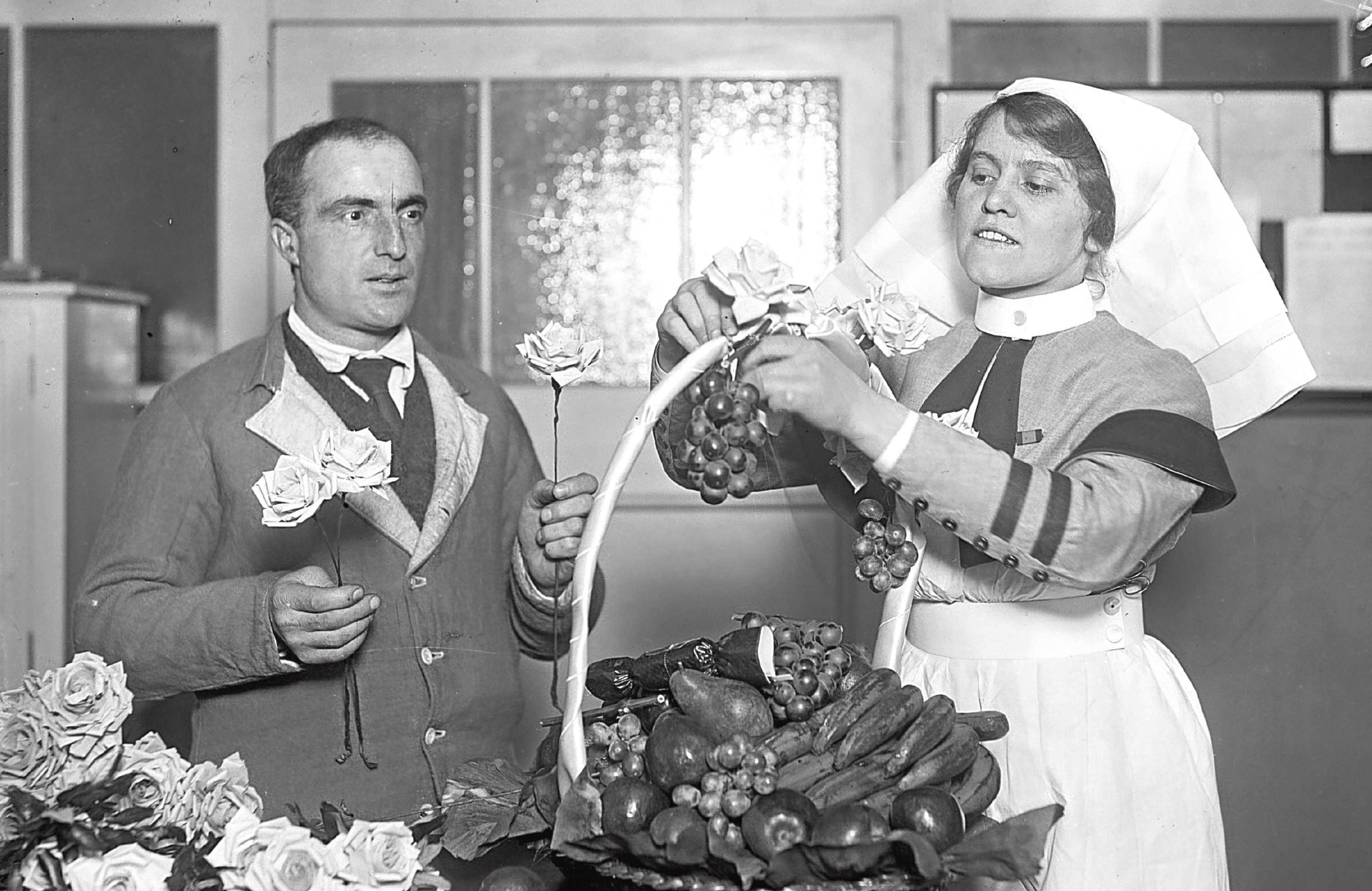 A nurse arranges a basket of fruit and flowers with the help of a patient at King George's Military Hospital  (Topical Press Agency/Getty Images)