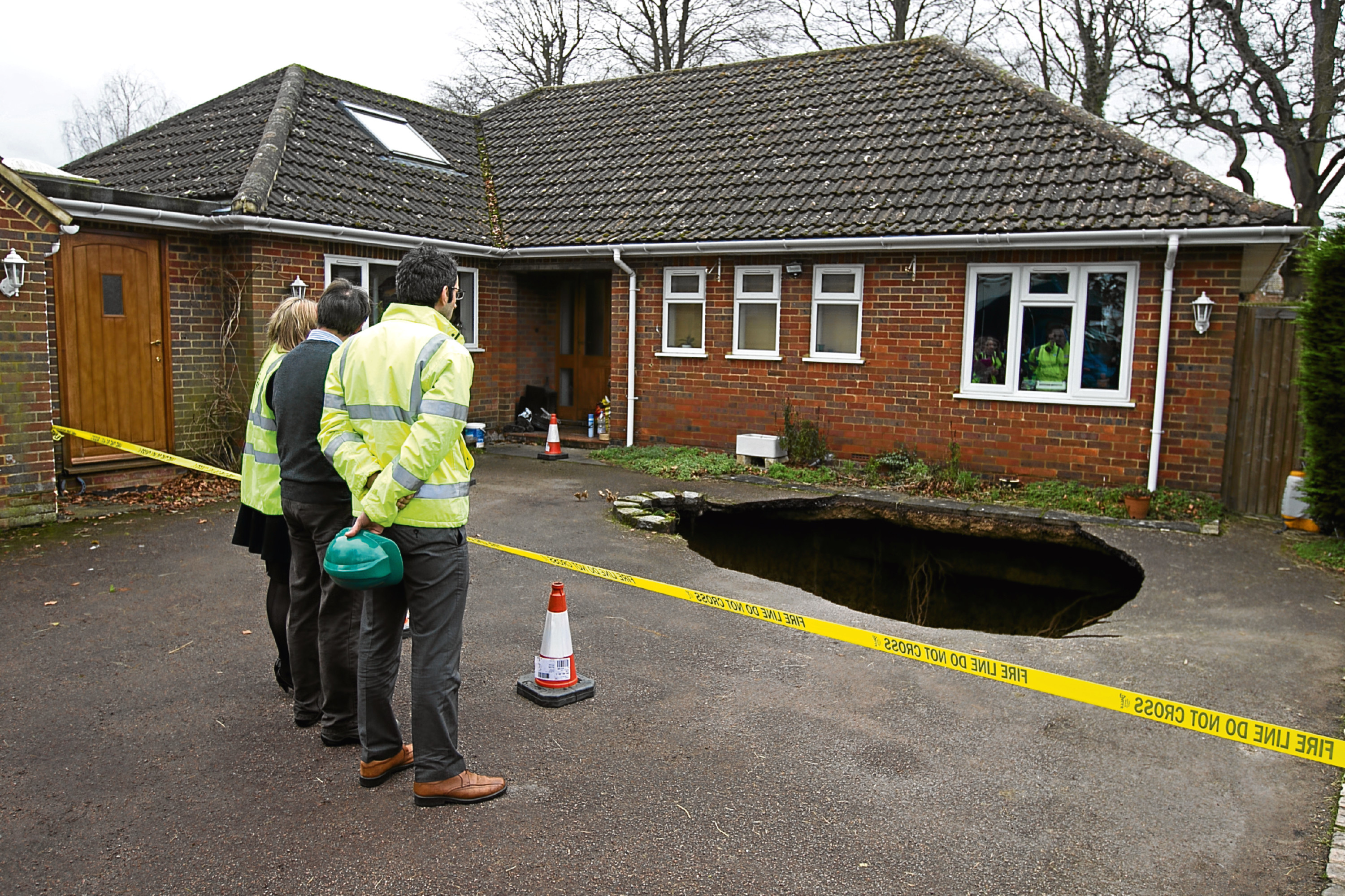 Surveyors at the home of Phil and Liz Conran, in Main Road, Walter's Ash, High Wycombe, Buckinghamshire, after a 30ft-deep sinkhole opened up in the driveway yesterday and swallowed his car.