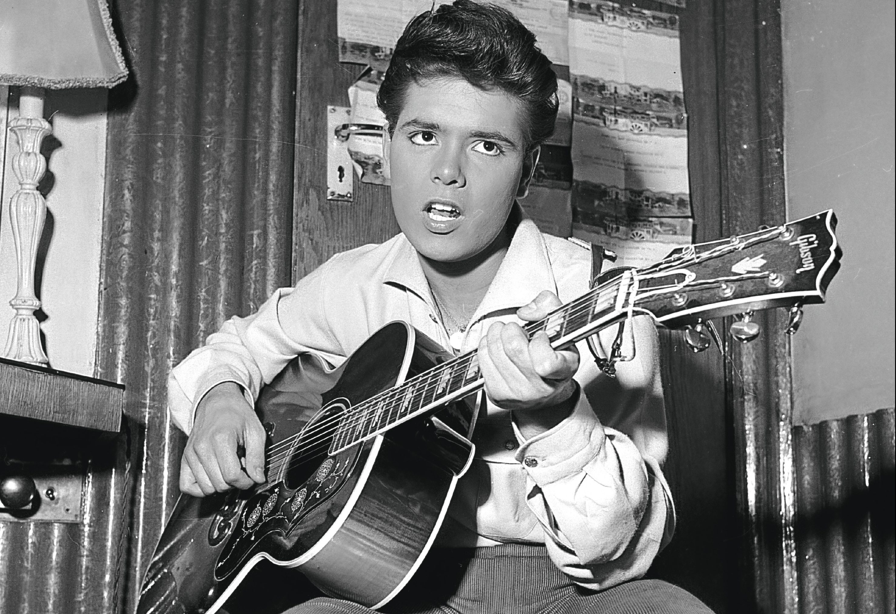 Cliff Richard strums a tune on his trusty guitar before a concert, 1960 (John Pratt/Keystone Features/Getty Images)