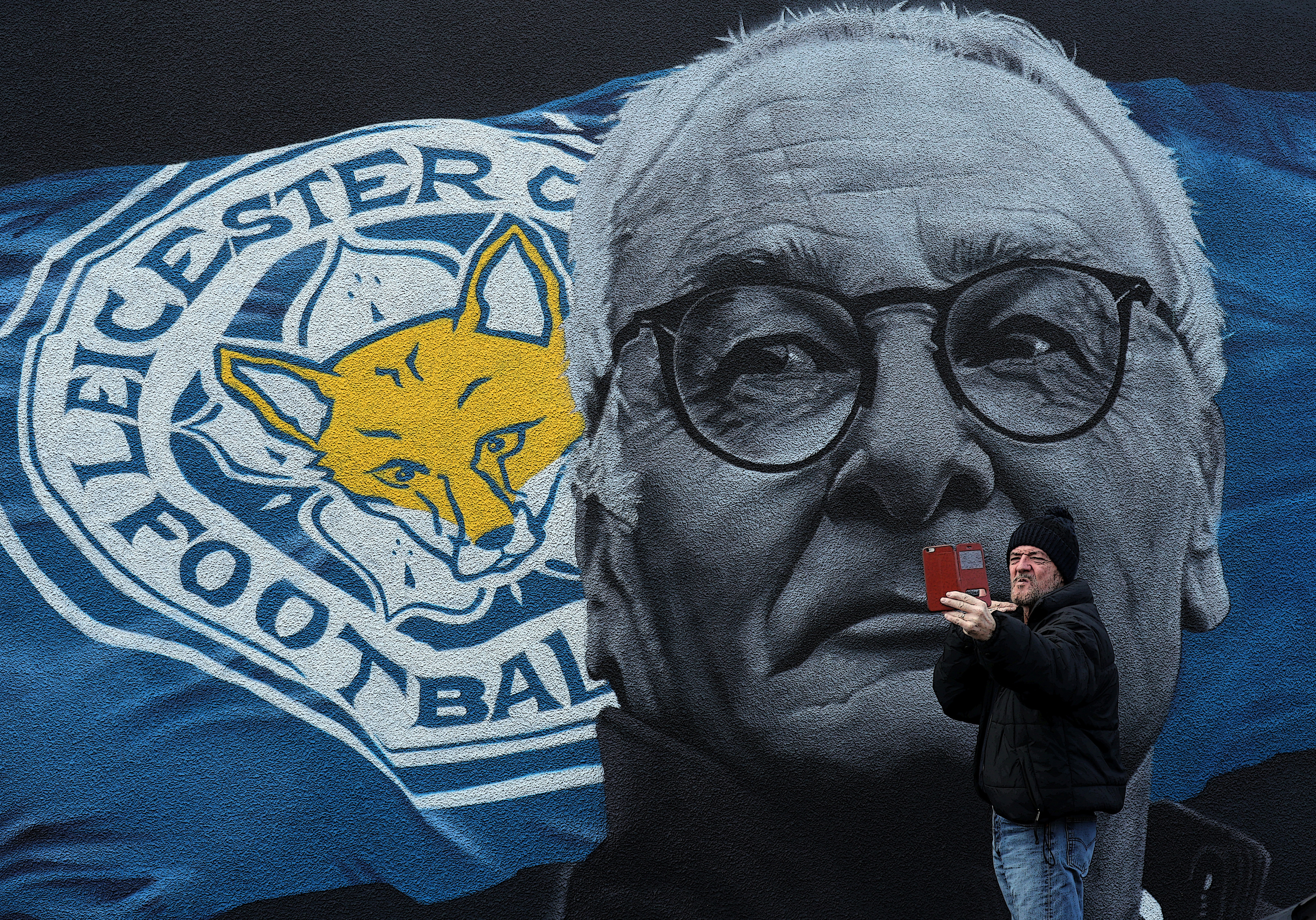A man takes a picture with a mural of Claudio Ranieri in Leicester city centre (PA)