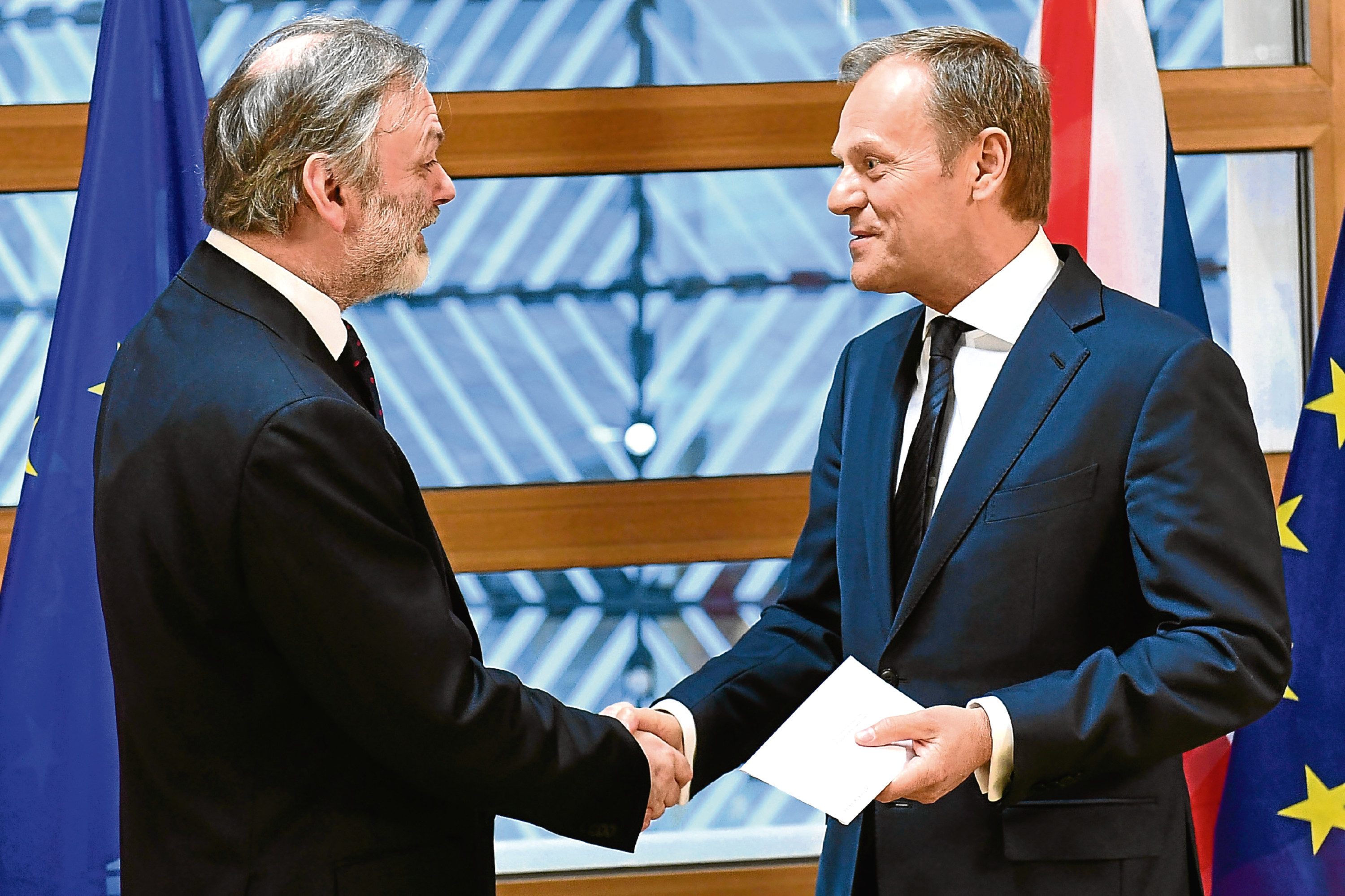 EU Council President Donald Tusk, right, shakes hands with UK Permanent Representative to the EU Tim Barrow after getting British Prime Minister Theresa May's formal notice to leave the bloc under Article 50 of the EU's Lisbon Treaty, in Brussels, Wednesday, March 29, 2017. (Emmanuel Dunand, Pool via AP)