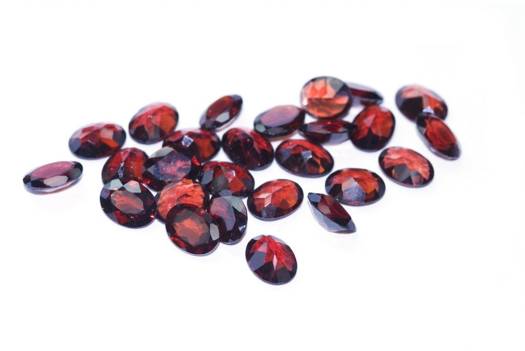 A collection of red garnet stones in a white background