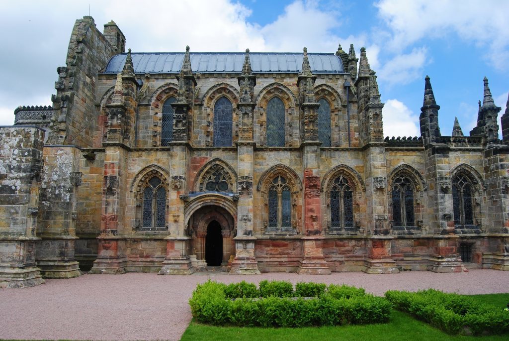 Roslin, United Kingdom - June 18, 2014. Exterior view of Rosslyn Chapel, with grass lawn, on cloudy summer day.