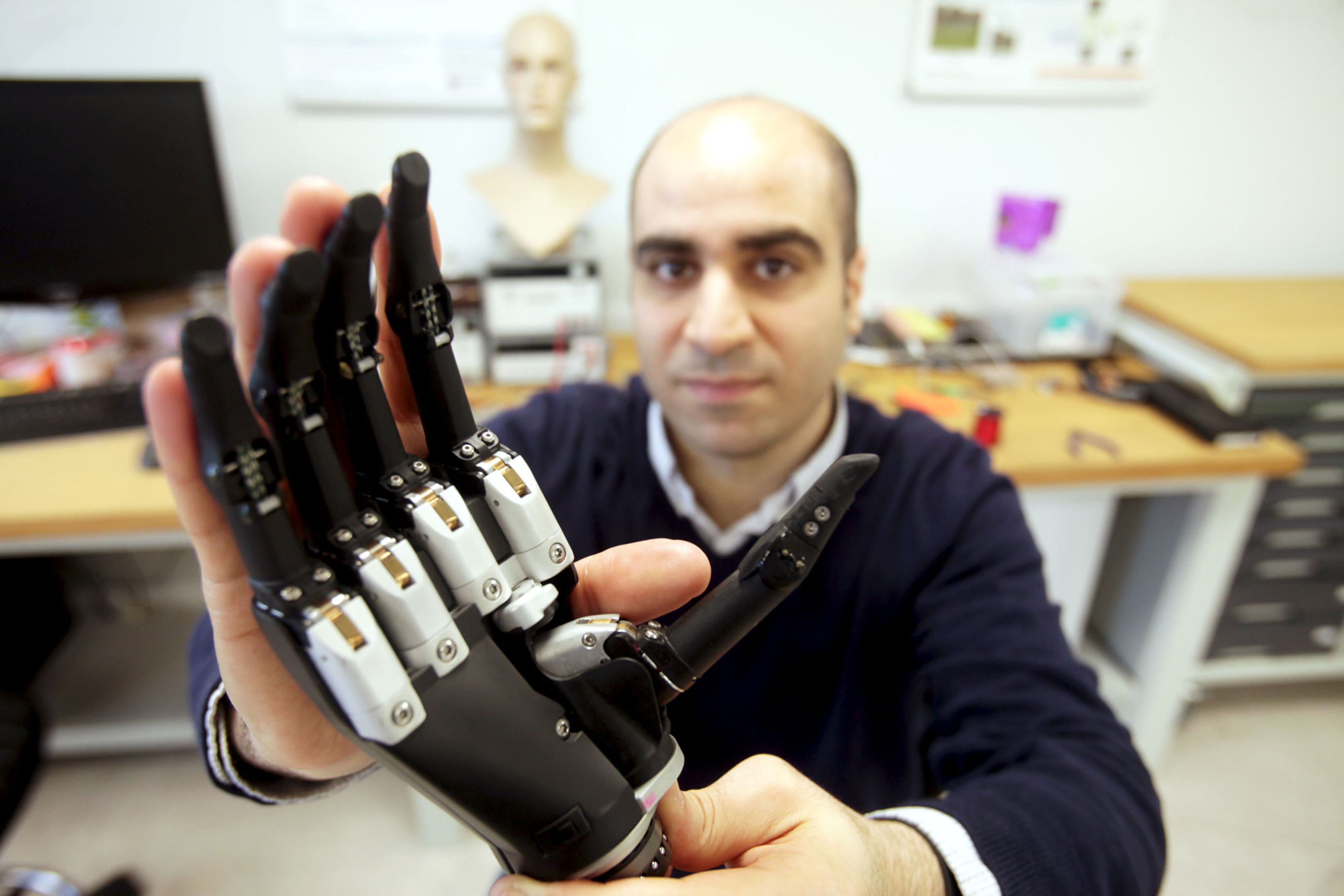 Dr. Kianoush Nazarpour from the university's Biomedical Engineering department with a new bionic hand that "sees" objects and instantly decides what kind of grip to adopt. (Mike Urwin/Newcastle University/PA Wire)