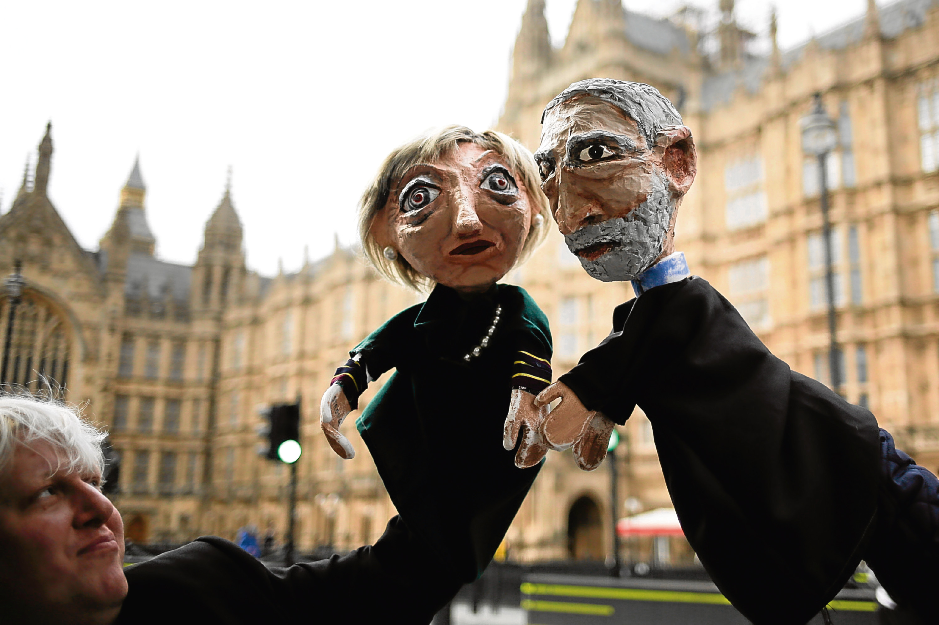 Two anti-Brexit activists pose with their hand-puppets depicting British Prime Minister and leader of the Conservative party Theresa May, left, and Britain's Labour party leader Jeremy Corbyn, in front of the Houses of Parliament. (AP Photo/Markus Schreiber)