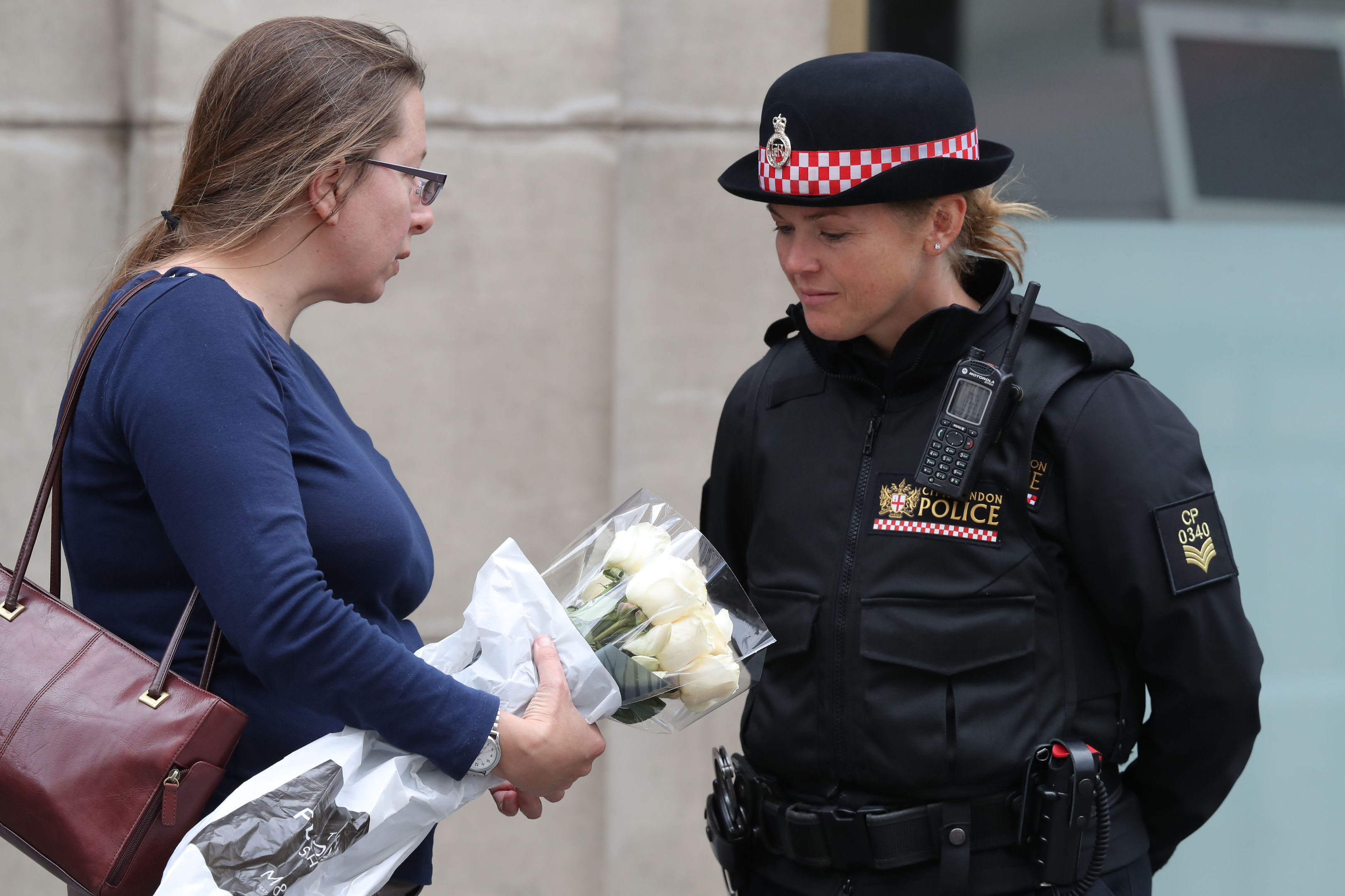 A member of the public speaks to a police officer as she brings flowers to lay on the north side of London Bridge following last night's terrorist incident (Andrew Matthews/PA Wire)