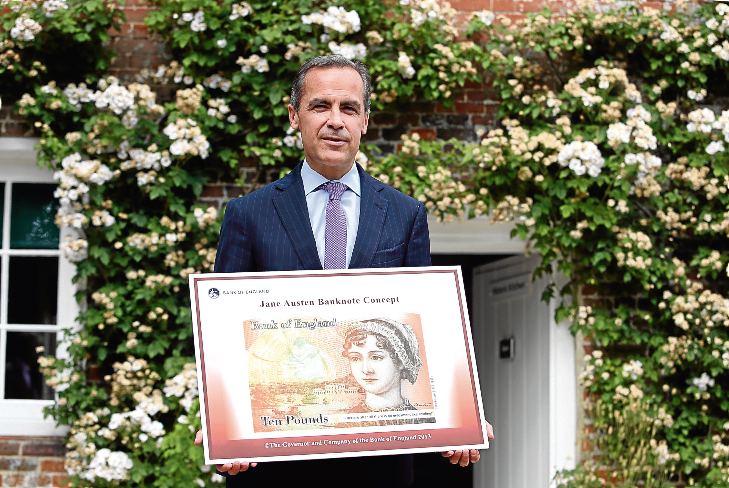 Governor of the Bank of England, Mark Carney stands holding the concept design for the new Bank of England ten pound banknote, featuring author Jane Austen, following the presentation at the Jane Austen House Museum , (Pool/Getty Images)