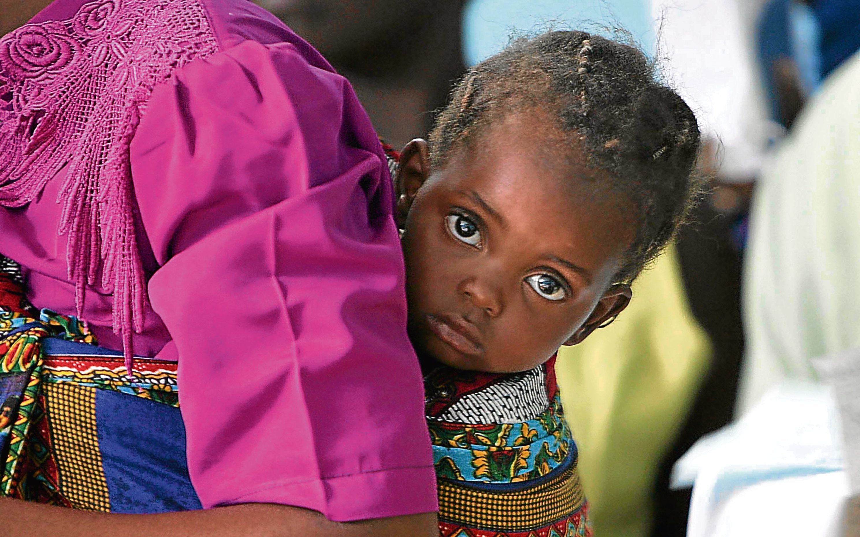 A young girl is seen on the back of her mother whilst she waits for treatment at Kamuzu Hospital, Malawi (Chris Jackson/Getty Images)