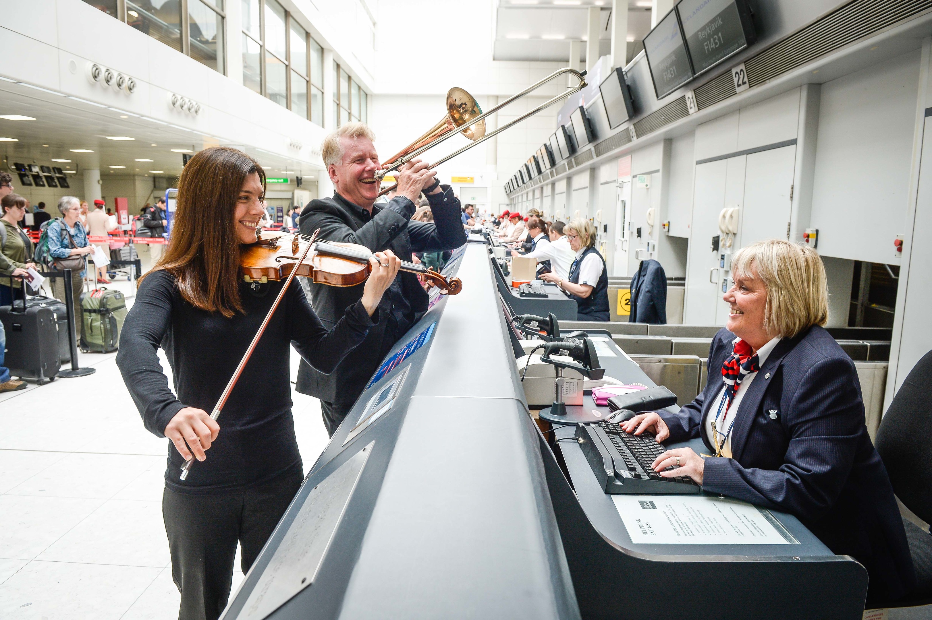 Passengers at Glasgow Airport today were invited to exercise their voices with the backing of the Royal Scottish National Orchestra (RSNO) and accompanied by dancers from Dance House Glasgow, as the nationÕs popular air terminal marks its 50th anniversary. l-r RSNO musicians Susannah Lowdon (Violin) and Lance Green (Trombone) with British Airways check in staff Linda Friel (Nick Ponty)