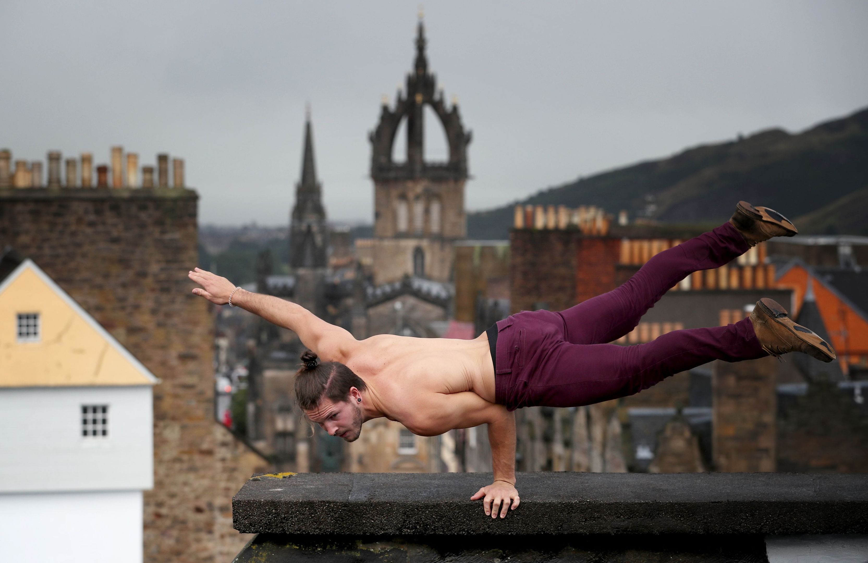 Cal Harris, a member of Head First Acrobats, balances on the roof of Camera Obscura and World of Illusions in Edinburgh, ahead of his Fringe Festival show Elixir. (Jane Barlow/PA Wire)