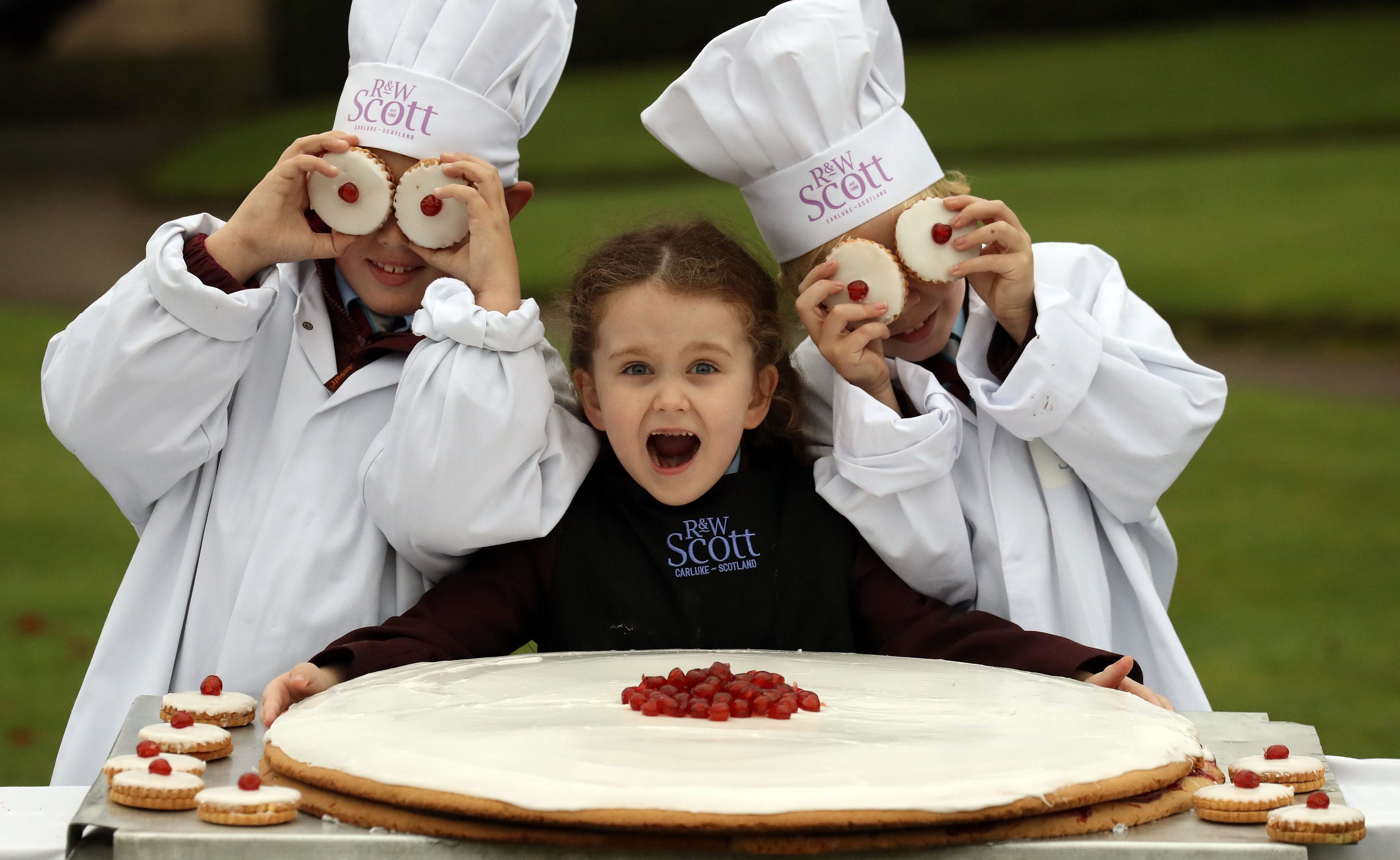 Local children l-r Jamie Gordon (10), Lana Irvine (6) and Joseph Irvine (8) with what is claimed to be the world's largest ever empire biscuit (Andrew Milligan/PA Wire)