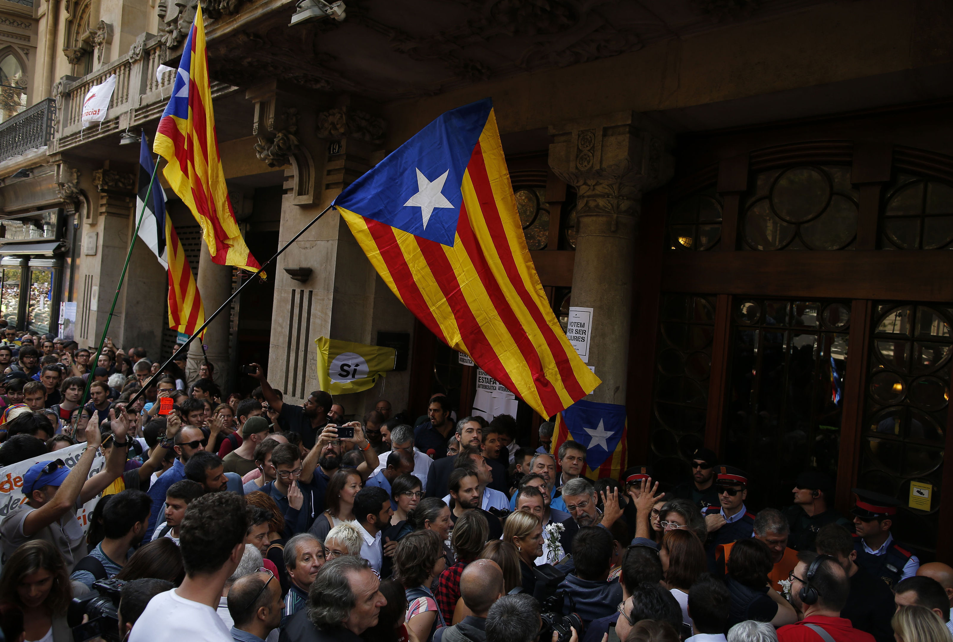 Pro-independence protestors hold up "esteladas", or independence flags, as they gather outside the headquarters of the region's department of economic affairs in Barcelona (AP Photo/Manu Fernandez)