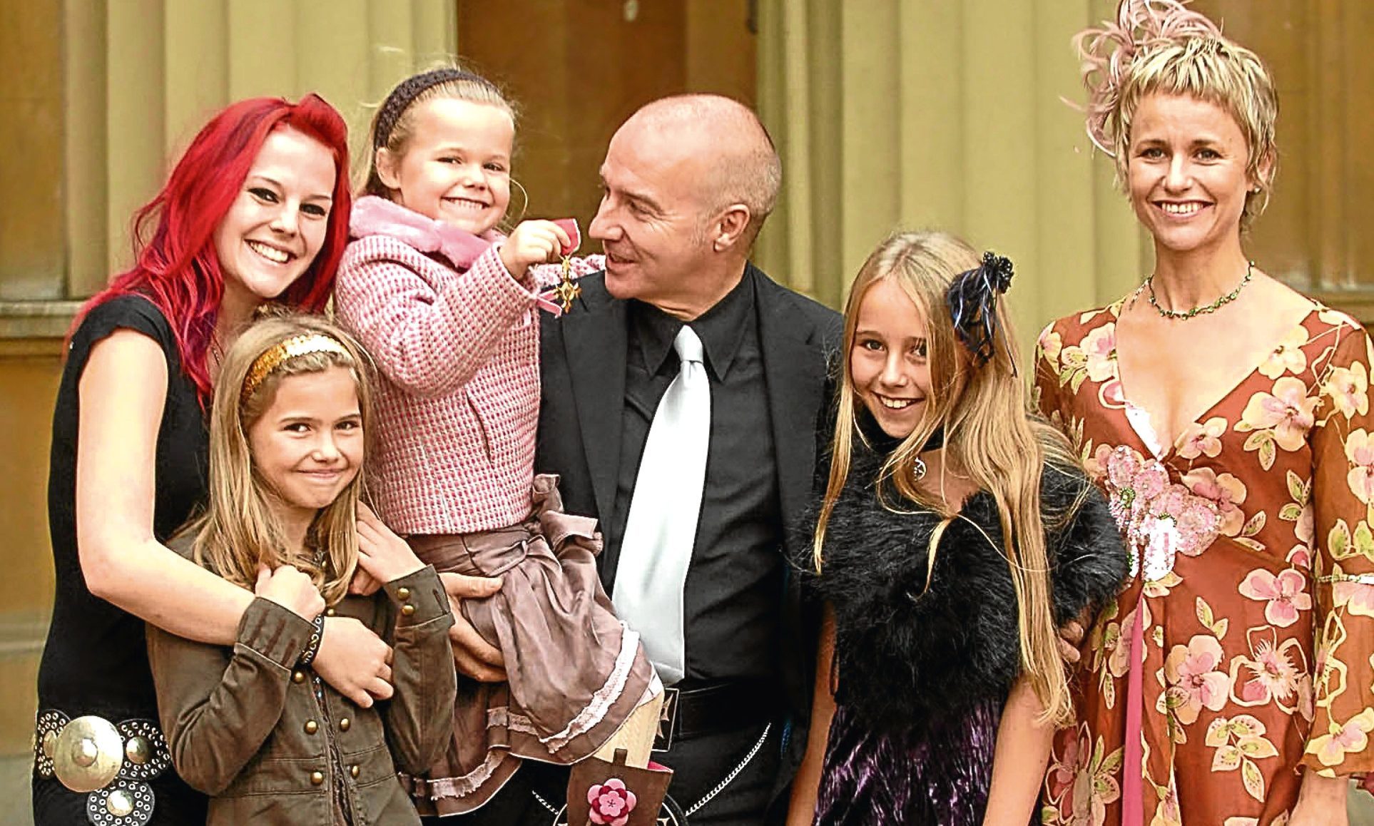 Proud Midge collecting his OBE in 2005 with his wife Sheridan and daughters Molly, Ruby, Flossie and Kitty (Brian Smith / REX / Shutterstock)