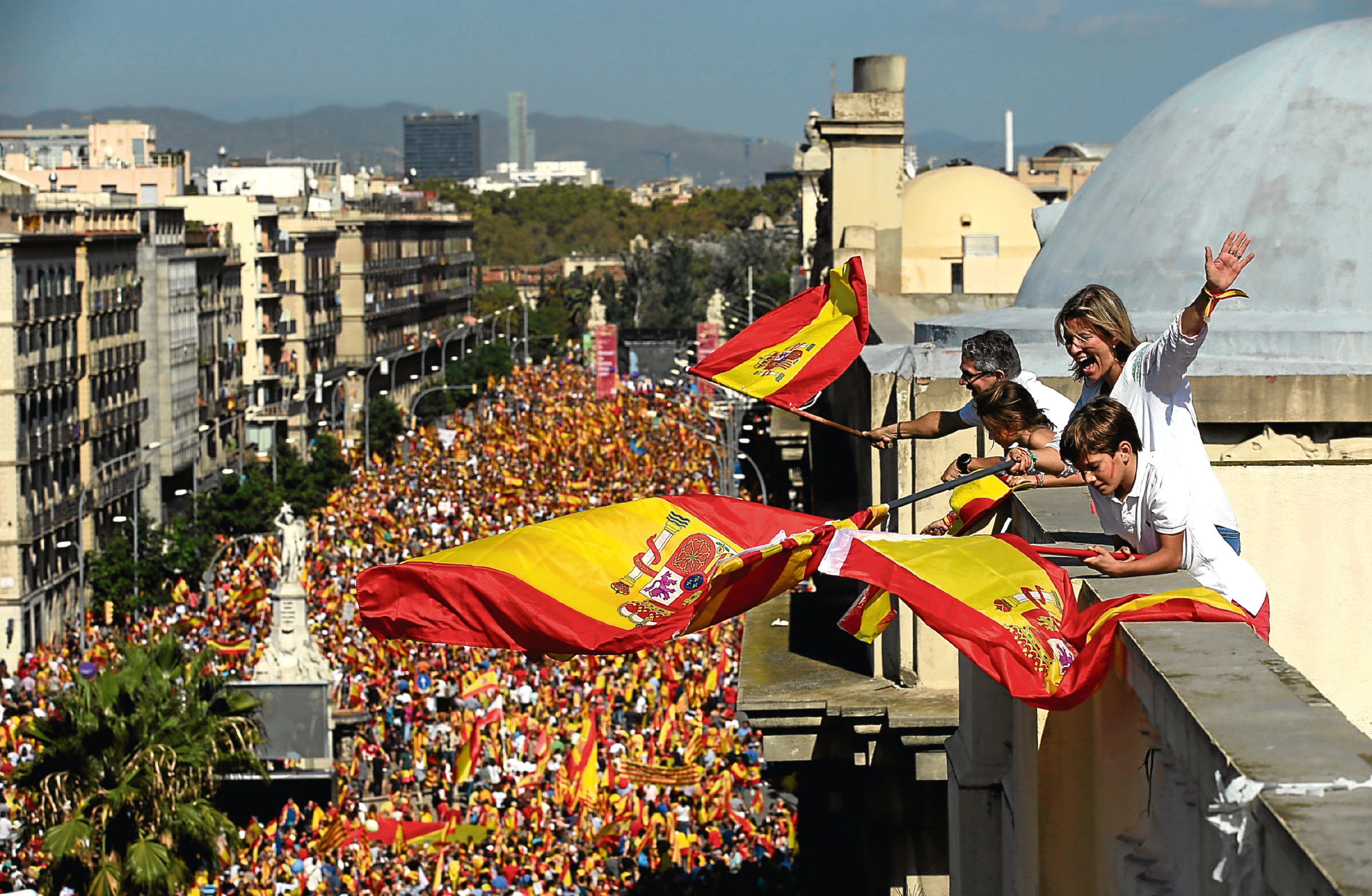 People on a rooftop wave Spanish flags during a march in downtown Barcelona, Spain, to protest the Catalan government's push for secession from the rest of Spain, Sunday Oct. 8, 2017. (AP Photo/Manu Fernandez)
