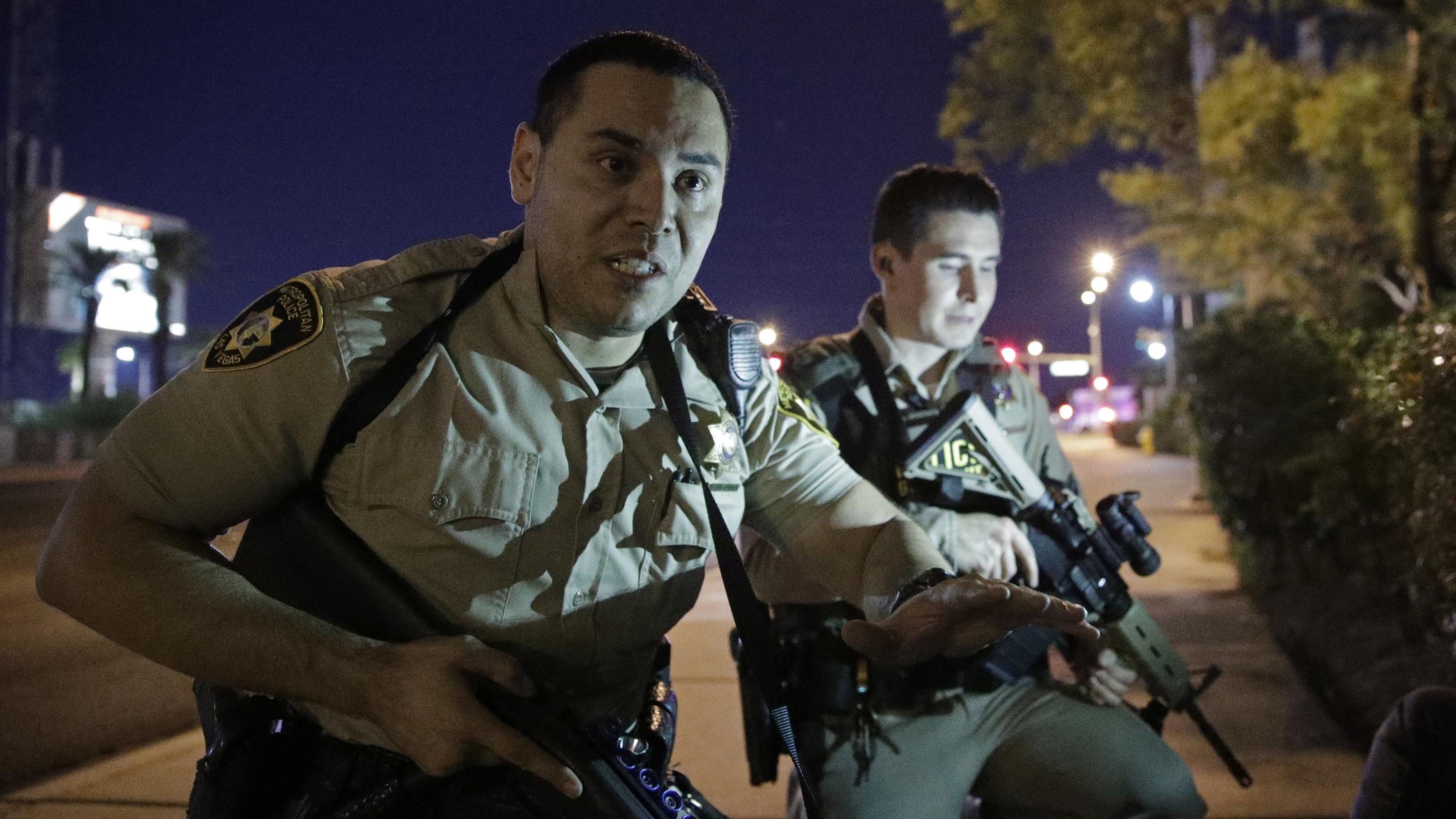 Police officers advise people to take cover near the scene of a shooting near the Mandalay Bay resort and casino on the Las Vegas Strip (John Locher/AP)