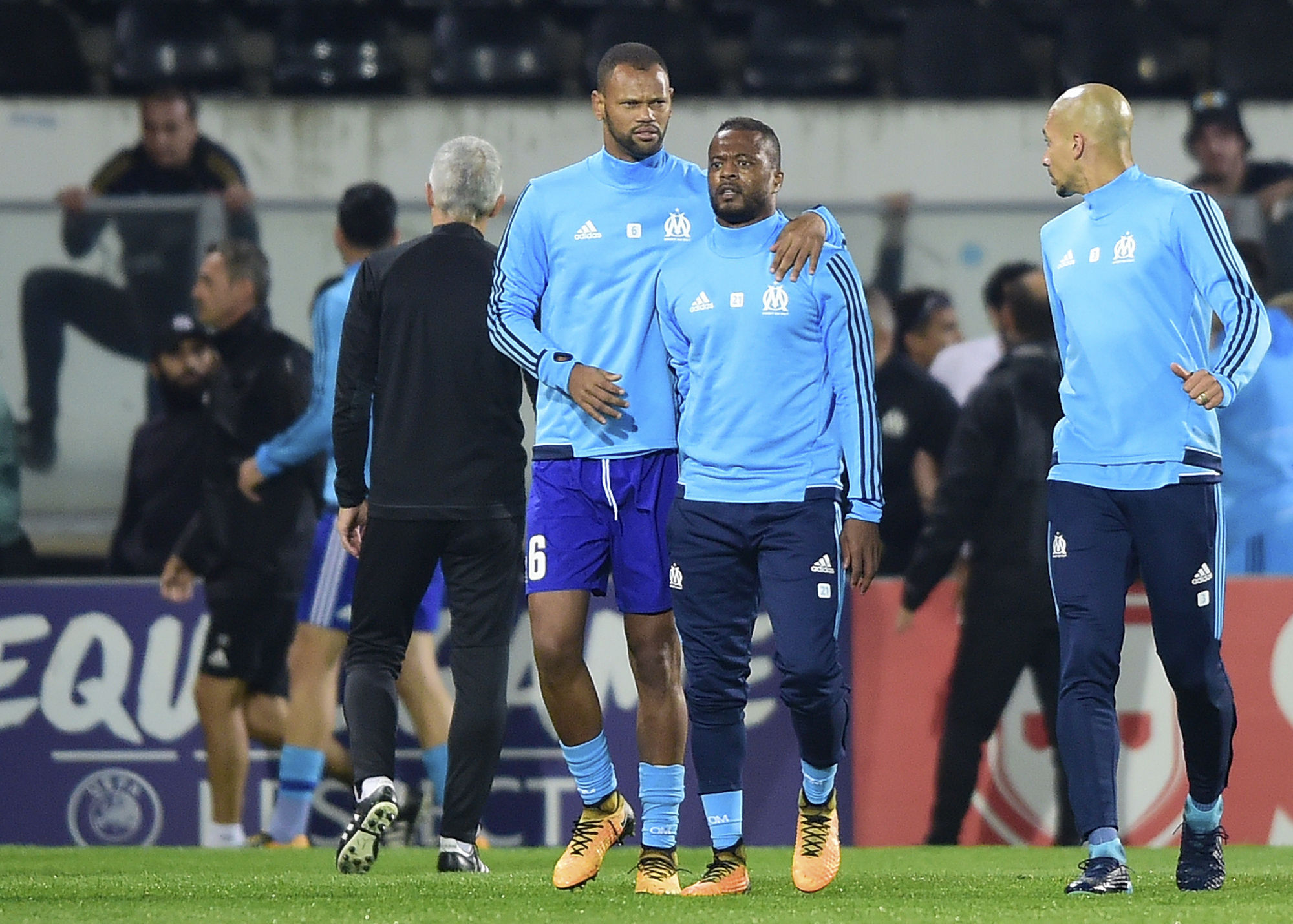 Marseille's Patrice Evra, center right, is led away by his teammate Rolando (AP Photo/Luis Vieira)