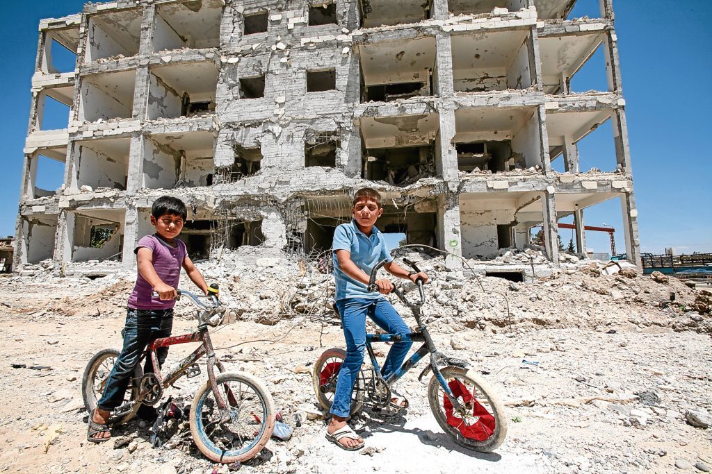 Children pose on their cycles in front of a destroyed building in the center of the Syrian town of Kobane, also known as Ain al-Arab, Syria. (Ahmet Sik/Getty Images)