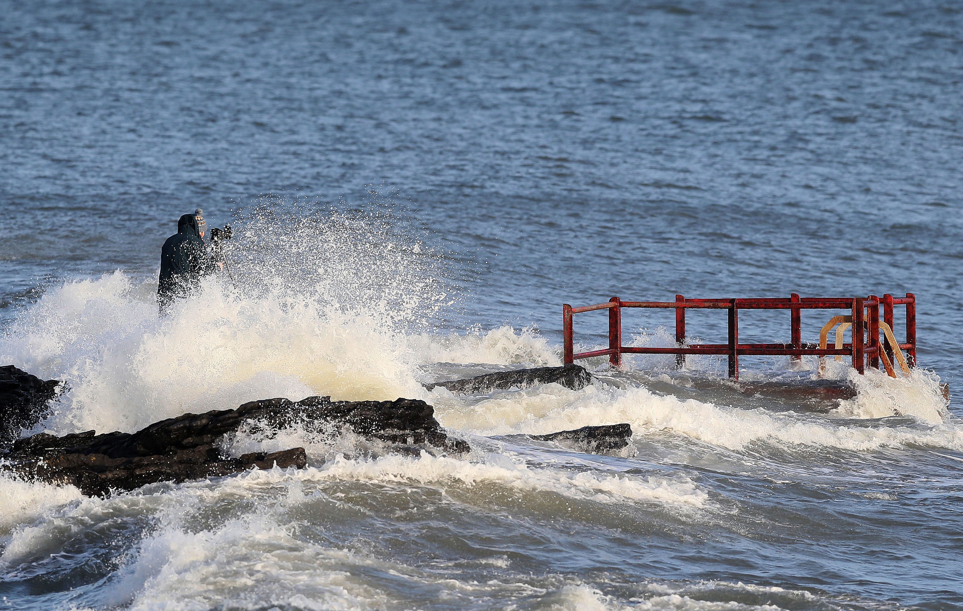 A man taking photographs gets caught by crashing waves at High Rock in Portmarnock, Dublin with the storm heading towards Scotland (Brian Lawless/PA Wire)
